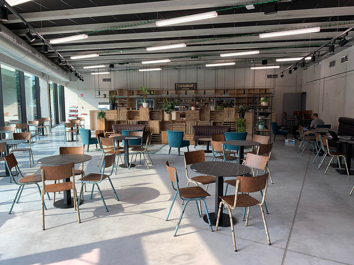 Terrastafels en stoelen op het zonnige terras van Cultuurcafé Merelbeke